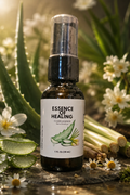 A 1 fl oz amber glass spray bottle labeled Clean Essence Hand Sanitizer by 'ESSENCE OF HEALING' with aloe and chamomile illustrations, surrounded by fresh aloe vera, chamomile flowers, and green leaves in a natural outdoor setting.