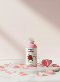 Bottle of 'Essence of Healing' Rose Essence Scented Body Oil Drops with a rose design on a light background with pink petals.